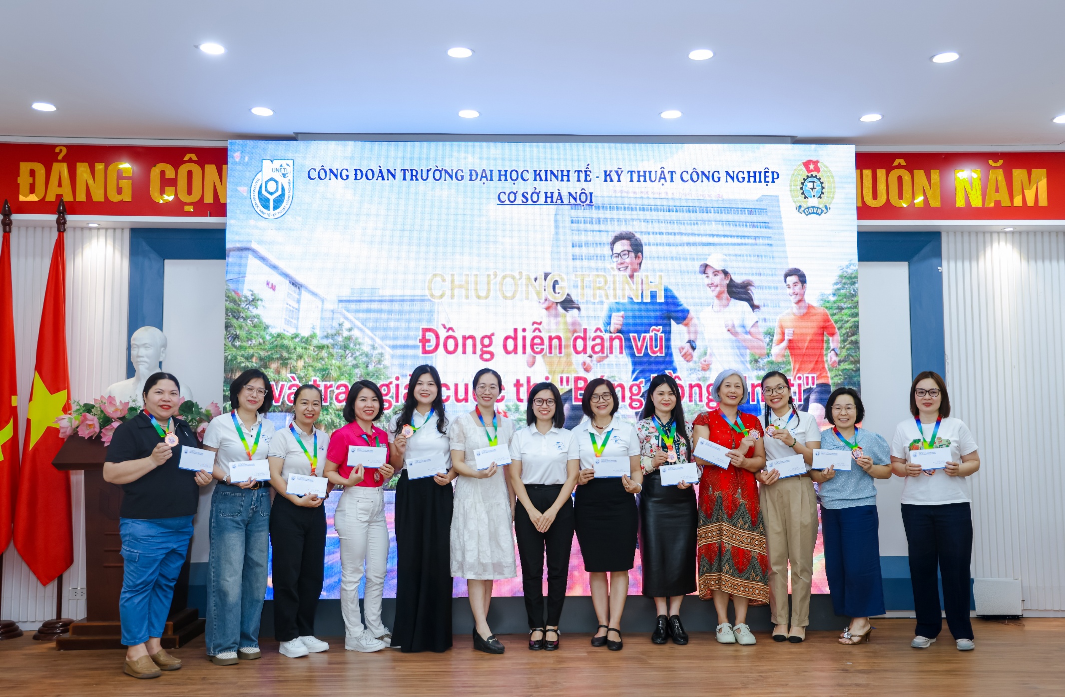A group of people standing in front of a large screen Description automatically generated