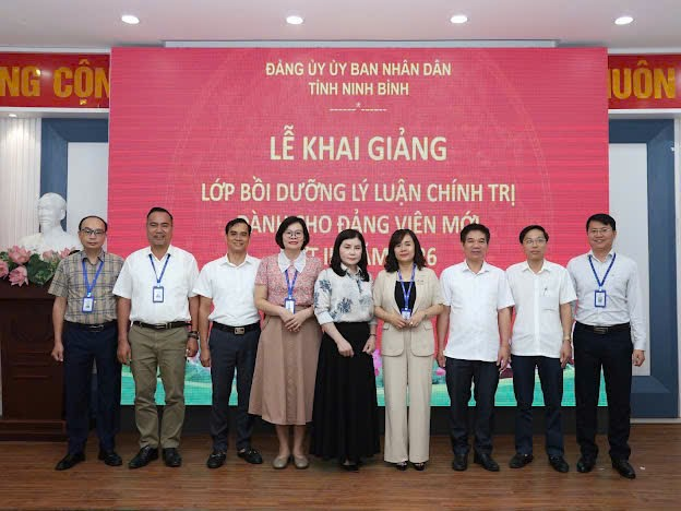 A group of people standing in front of a large screen Description automatically generated