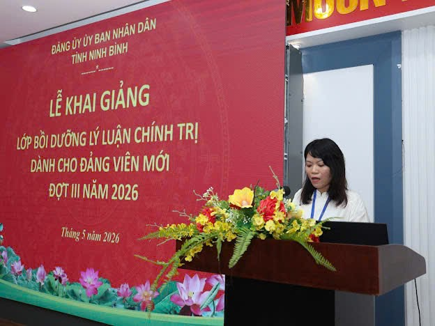 A person standing behind a podium with a red sign Description automatically generated