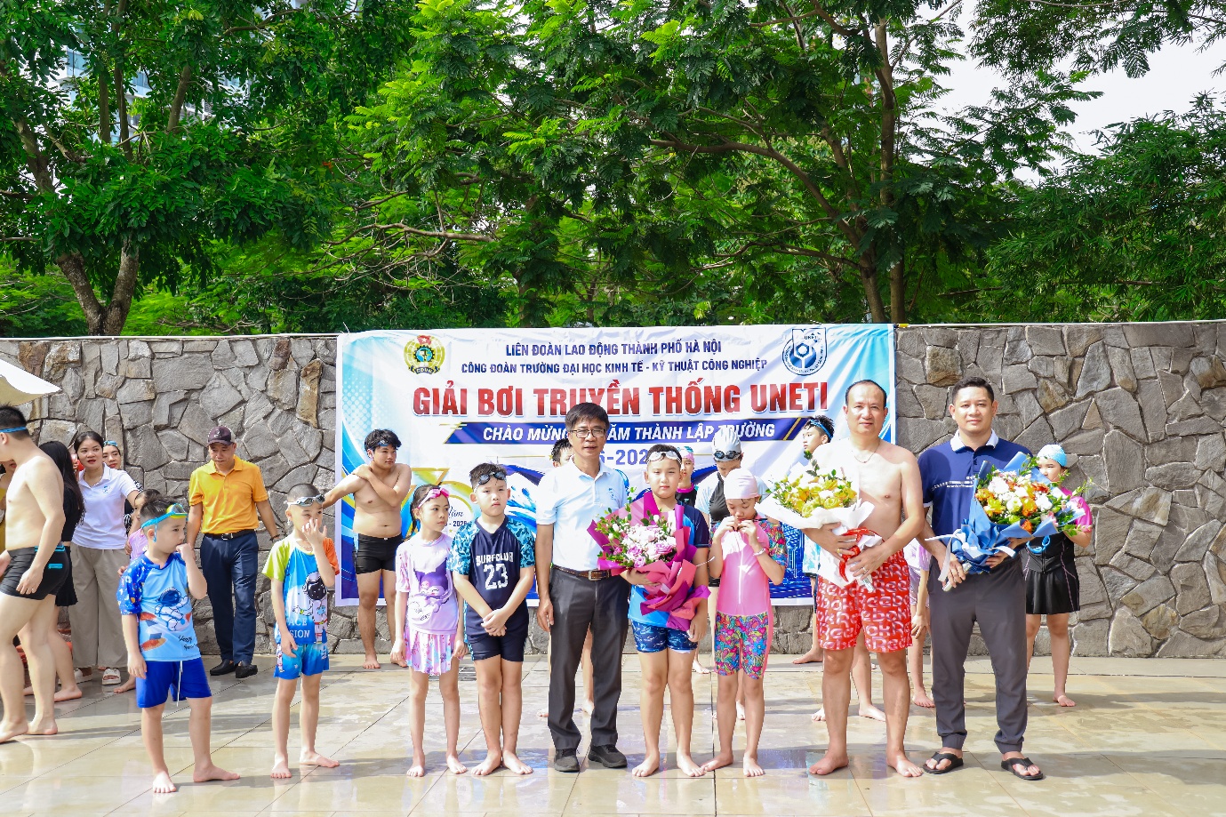 A group of people standing in front of a banner Description automatically generated