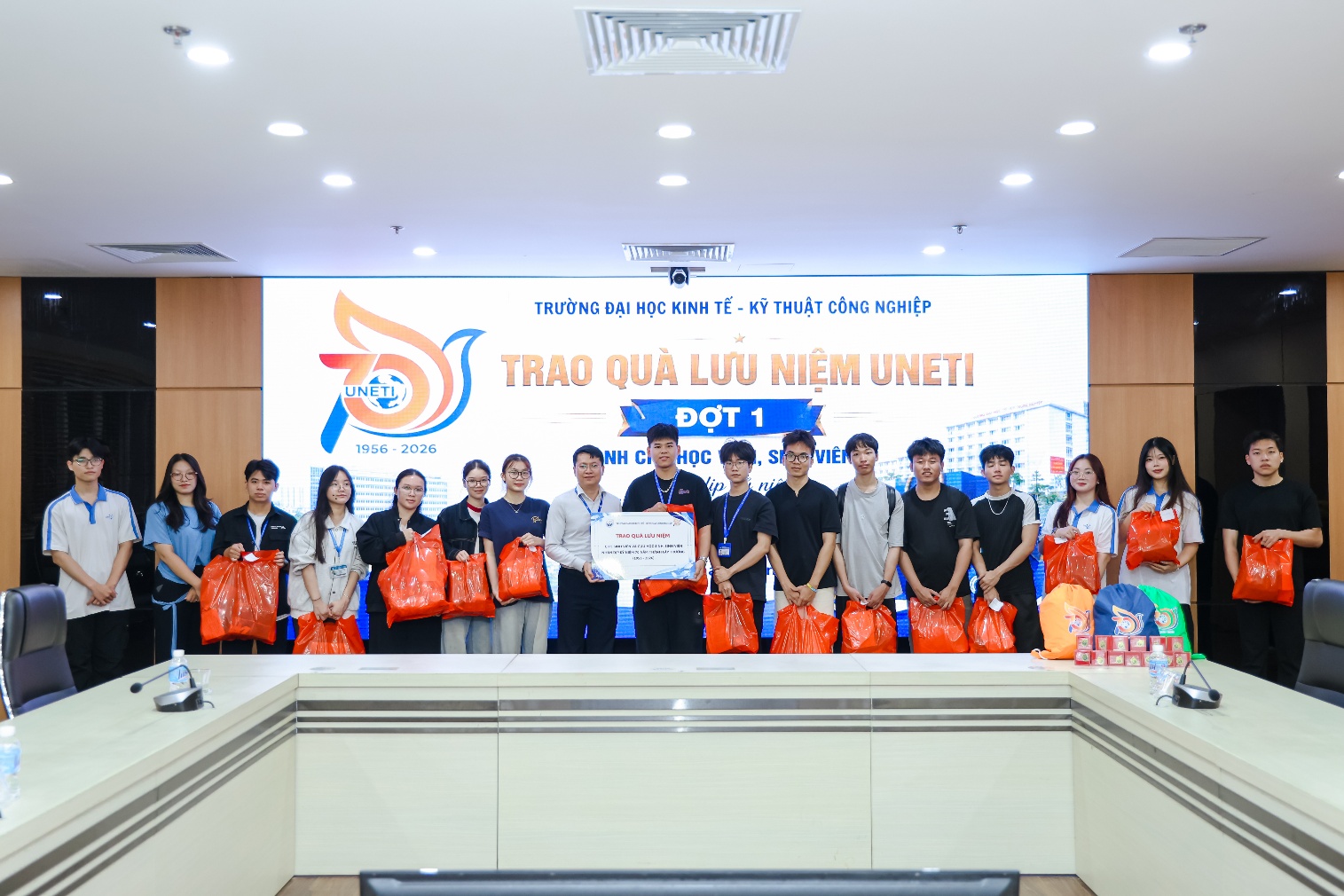 A group of people standing in front of a large sign
Description automatically generated
