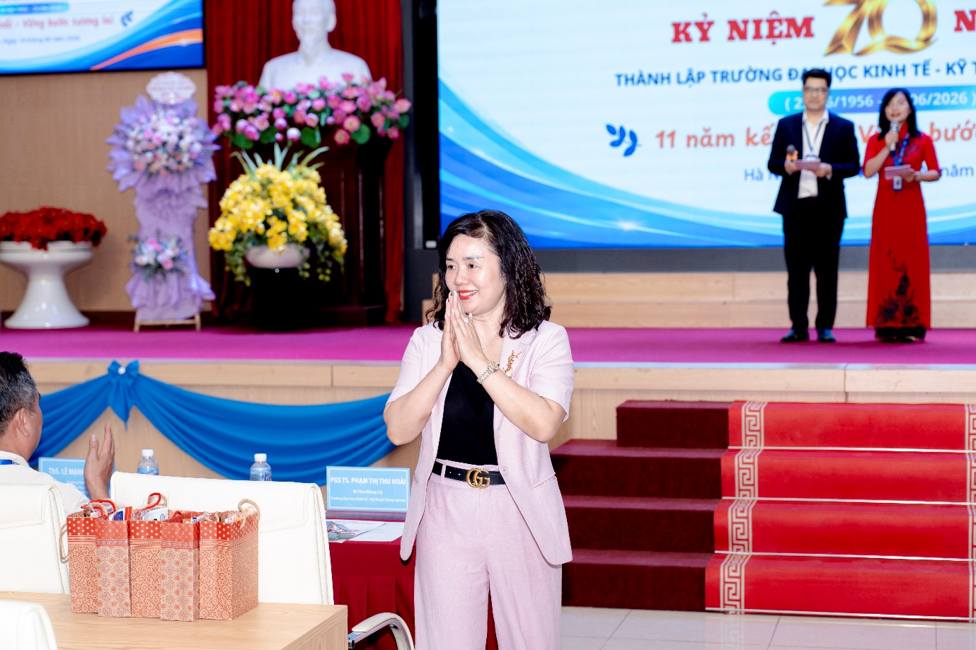 A person standing in front of a stage with her hands together

Description automatically generated