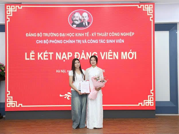 Two women standing in front of a large sign
Description automatically generated