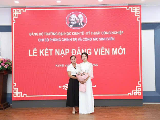 Two women standing in front of a large sign
Description automatically generated