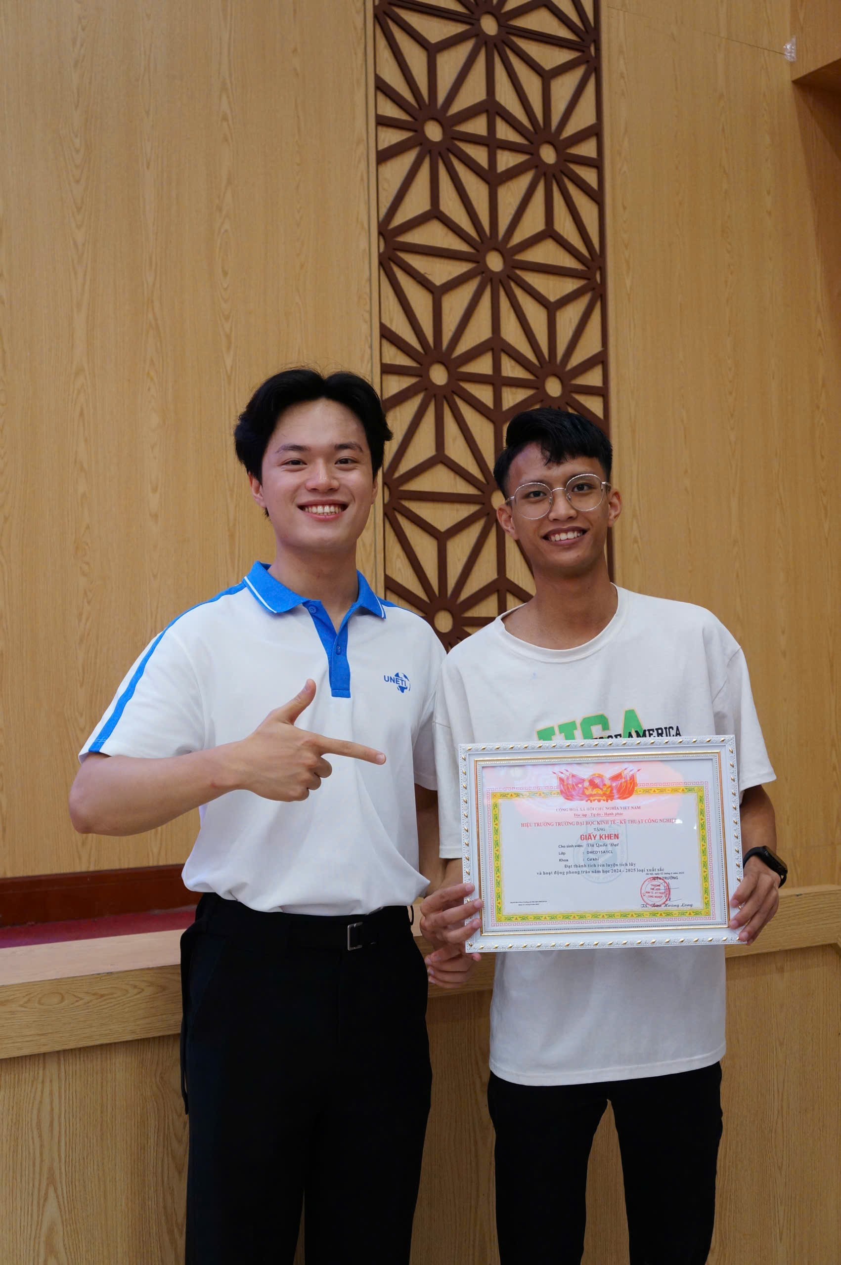 A couple of men holding a certificate Description automatically generated